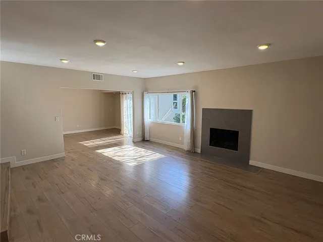 a view of empty room with wooden floor and fireplace