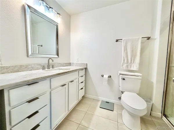 a bathroom with a granite countertop toilet sink and mirror