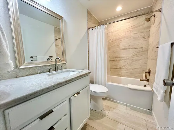 a bathroom with a granite countertop sink toilet and shower