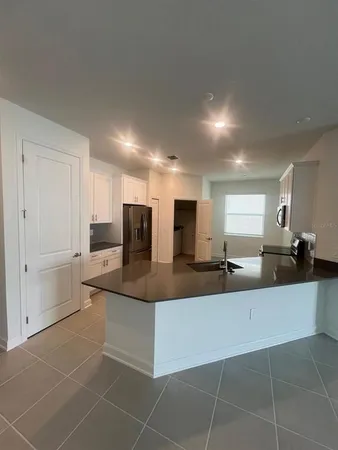 a large kitchen with kitchen island a sink a counter and a view of living room