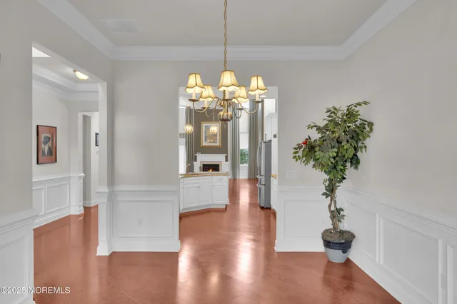 a view of a hallway with wooden floor and a chandelier
