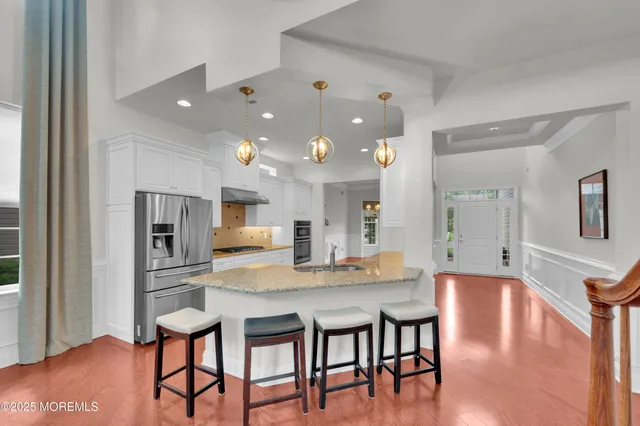 a kitchen with stainless steel appliances granite countertop a kitchen island and chairs in it