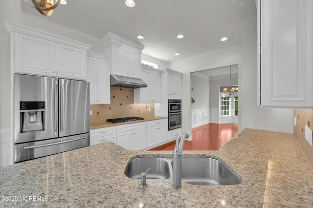 a kitchen with stainless steel appliances granite countertop a sink refrigerator and cabinets