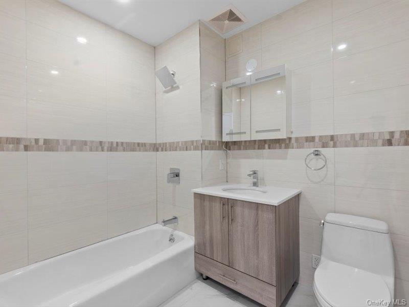 124-28 Queens Boulevard, Unit PHA Queens, NY 11415 - Photo 13 of 15 Bathroom with tile walls, vanity, and shower combination