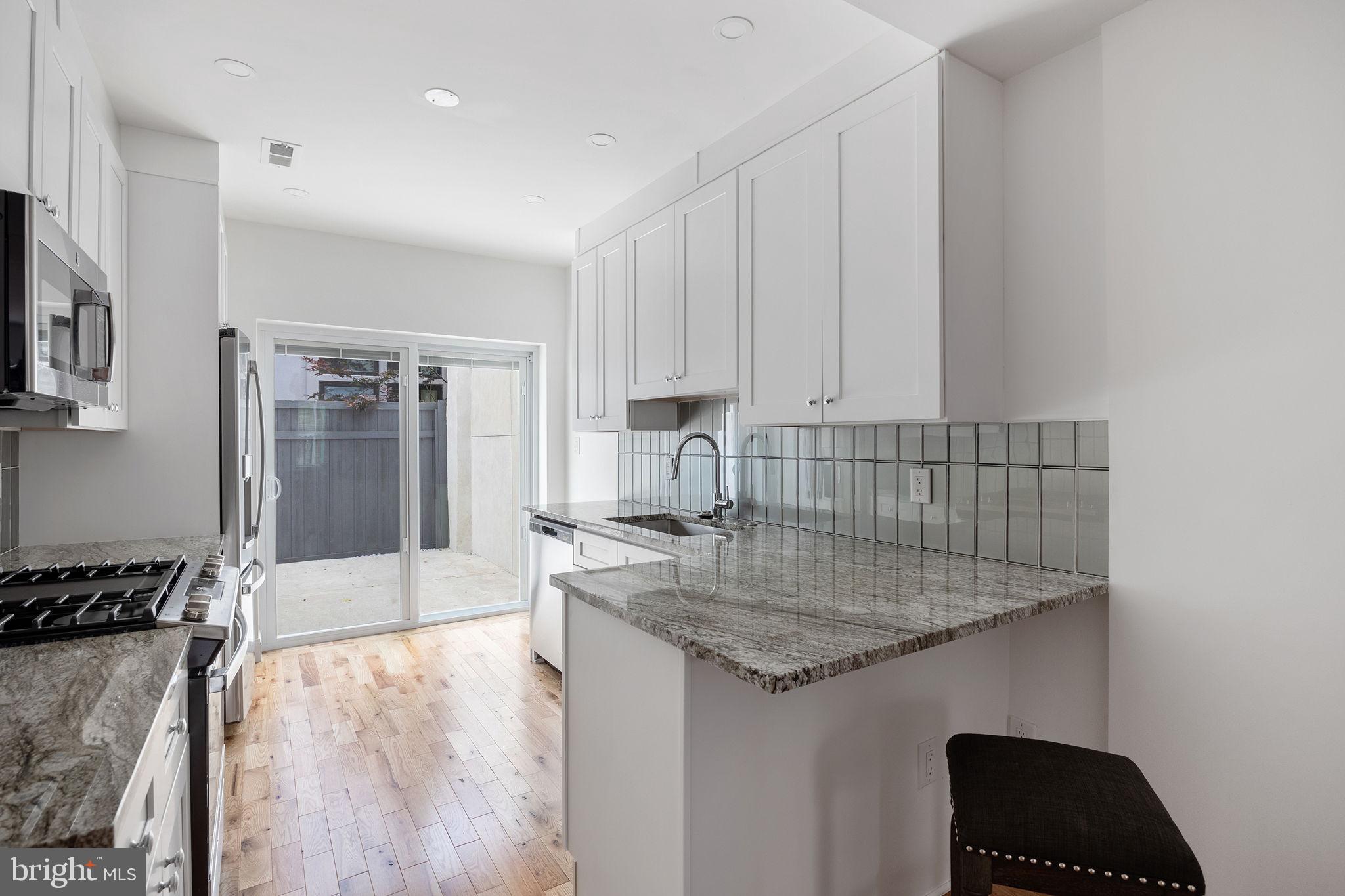 811 Kimball Street Philadelphia, PA 19147 - Photo 13 of 37 a kitchen with granite countertop a stove and white cabinets