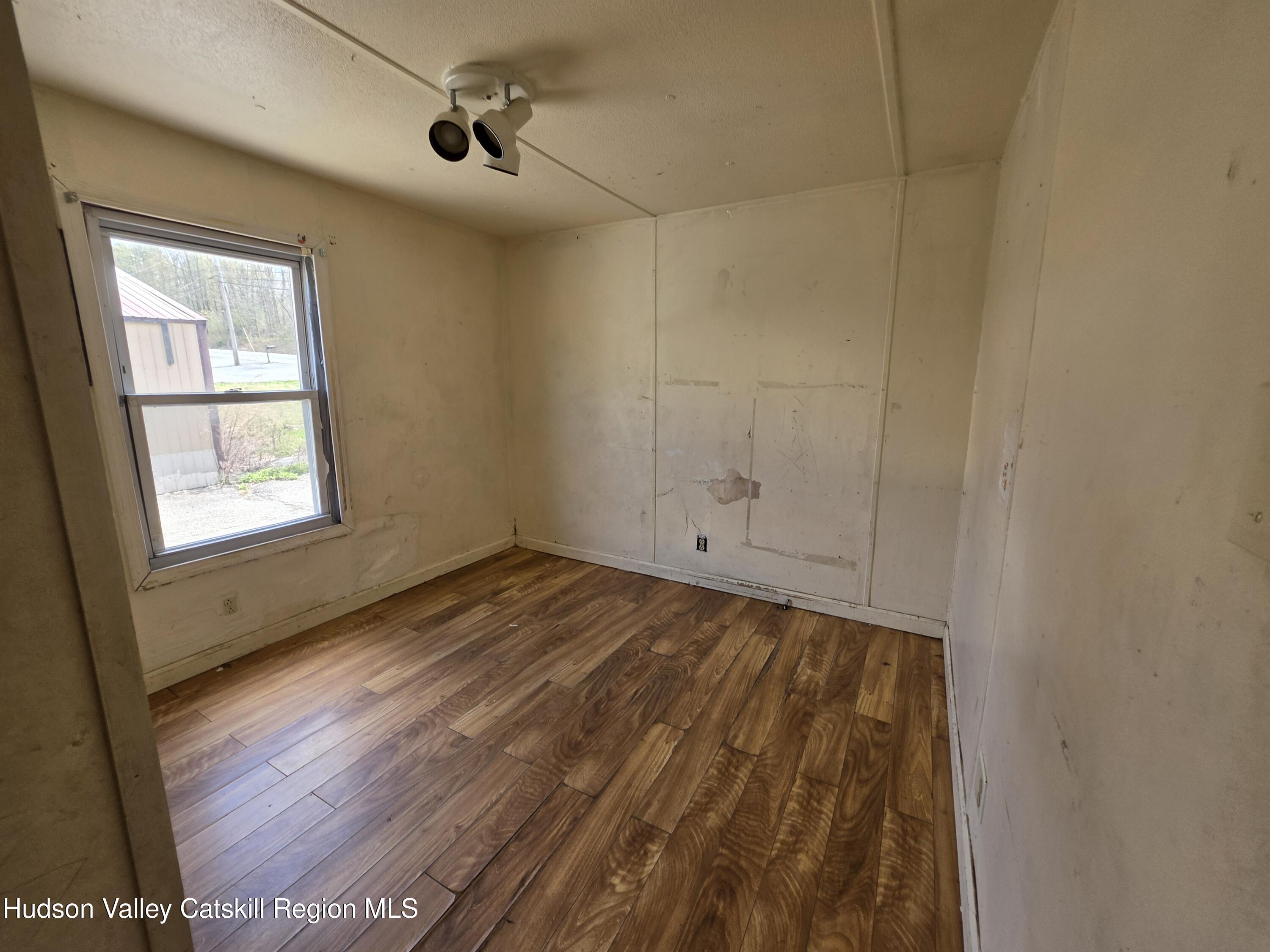 852 State Rt 17B Monticello, NY 12701 - Photo 14 of 26 an empty room with wooden floor cabinet and windows