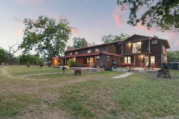 a view of a big house with a big yard and large trees