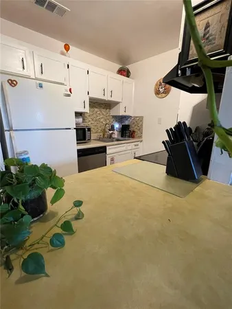 a kitchen with stainless steel appliances kitchen island granite countertop a refrigerator a stove a sink and white cabinets