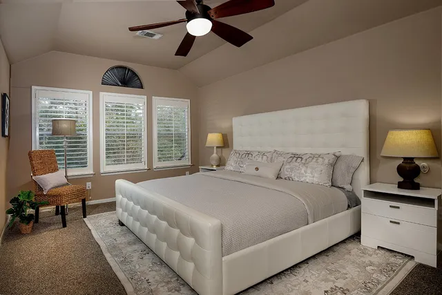 a spacious bedroom with a bed a couch and a chandelier