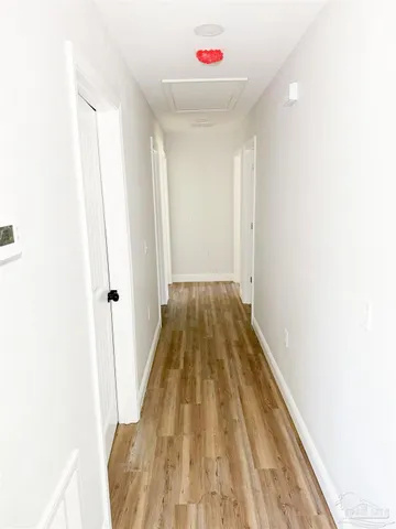 a view of a hallway with wooden floor and a bathroom