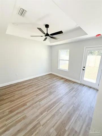 an empty room with wooden floor fan and windows