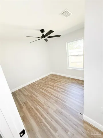 a view of a room with wooden floor and a ceiling fan