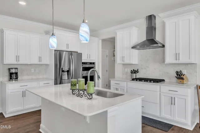 a kitchen with stainless steel appliances a sink a stove a refrigerator cabinets and chairs