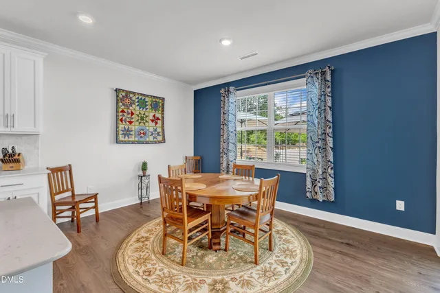 a kitchen with kitchen island granite countertop a stove a sink a dining table and chairs with wooden floor