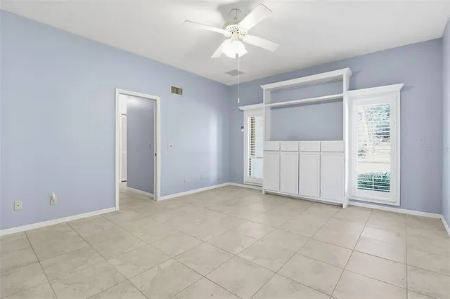 an empty room with windows and fan