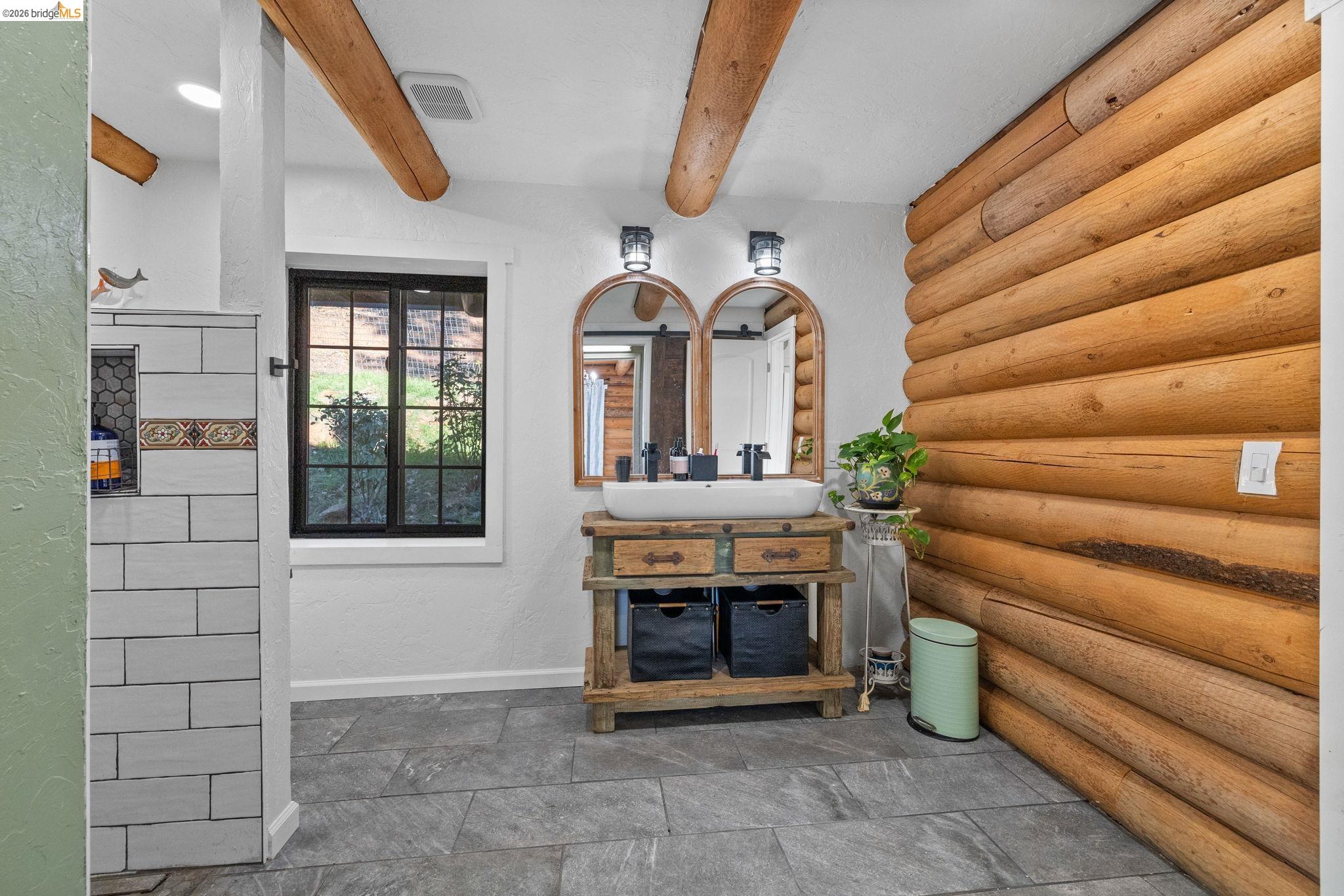 16144 Big Hill Road Sonora, CA 95370 - Photo 25 of 51 Log-style wall paneling and exposed wood beams frame this bathroom space