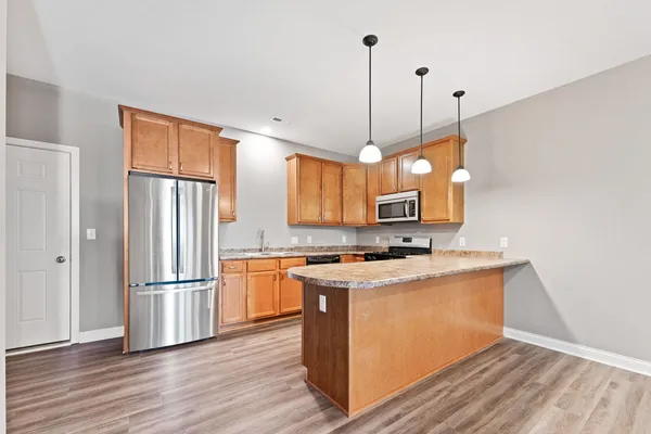 a kitchen with stainless steel appliances granite countertop a refrigerator a stove a sink and a wooden floor