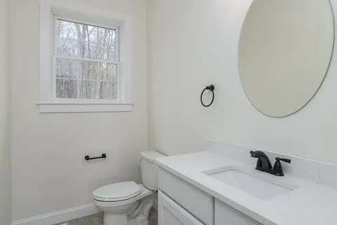 a bathroom with a granite countertop sink a toilet and a mirror