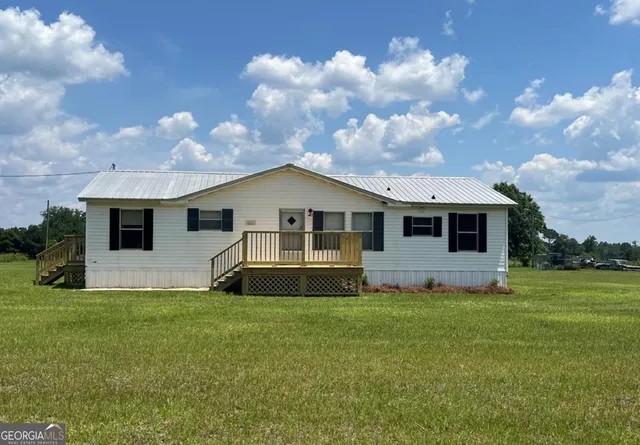 a front view of house with yard and trees in the background