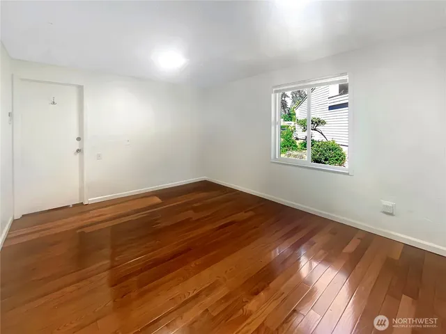 a view of empty room with window and wooden floor