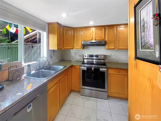 a kitchen with stainless steel appliances granite countertop a sink and a stove
