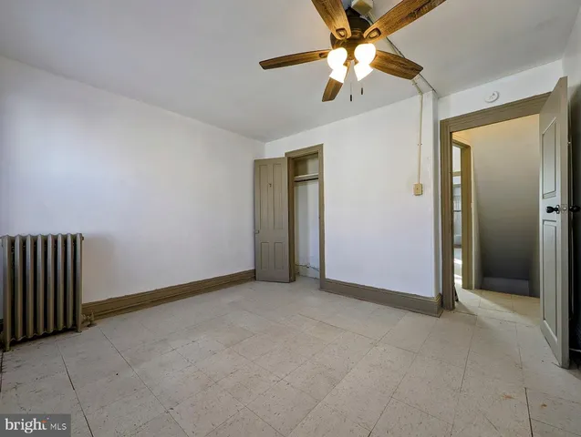 an empty room with closet and a chandelier fan