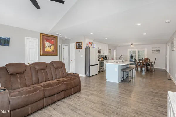 a living room with furniture and kitchen view with wooden floor