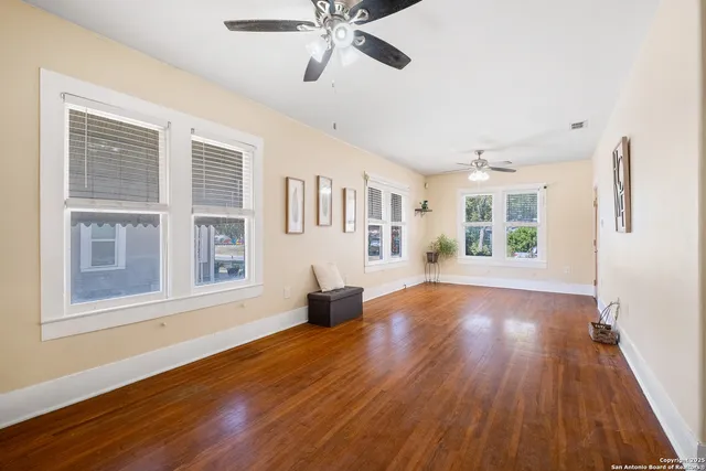 a view of an empty room with wooden floor and a window