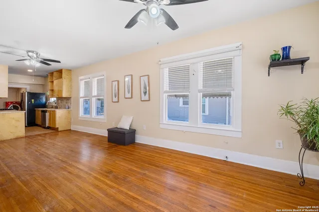 a view of an empty room with a window and wooden floor