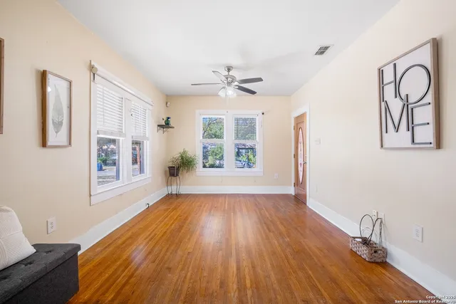 a view of an empty room with window and wooden floor
