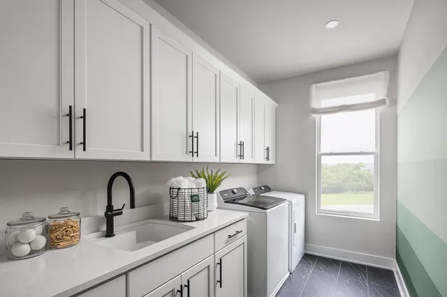 a kitchen with stainless steel appliances granite countertop a sink a window and white cabinets