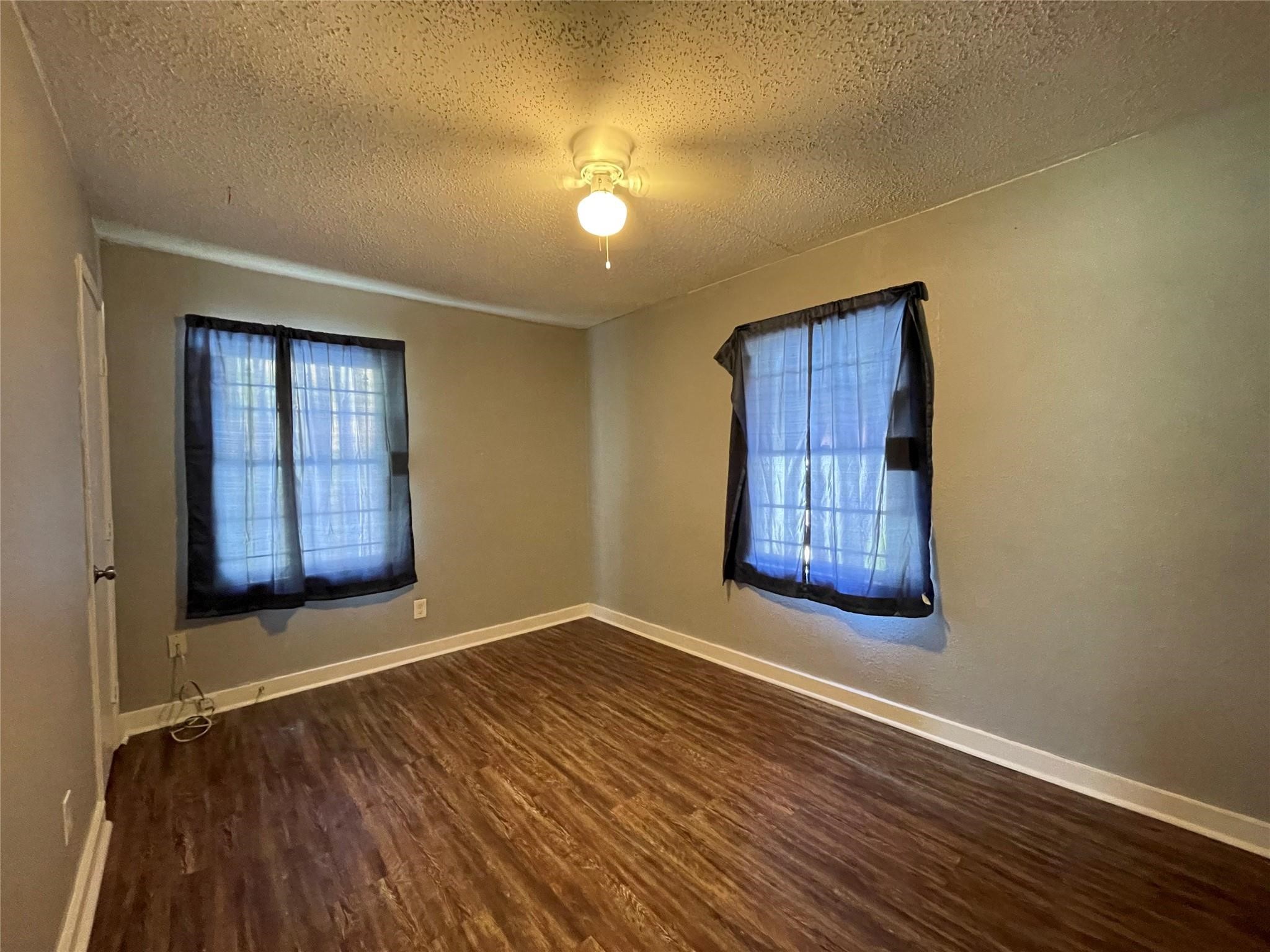 5213 Anzio Road Houston, TX 77033 - Photo 12 of 20 a view of an empty room with wooden floor and a window