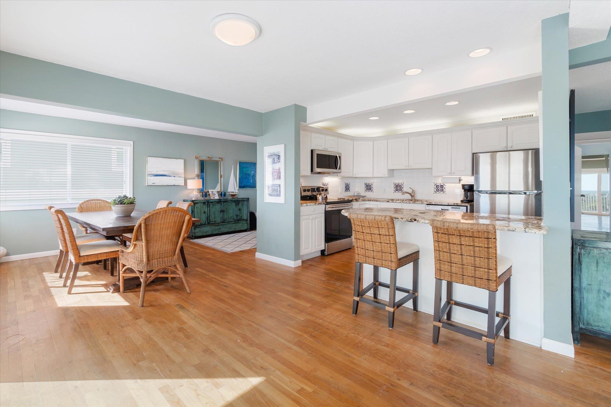 5512 Atlantic View St. Augustine, FL 32080 - Photo 12 of 77 Kitchen featuring white cabinets, stainless steel appliances, light stone countertops, a breakfast bar, and light wood-type flooring