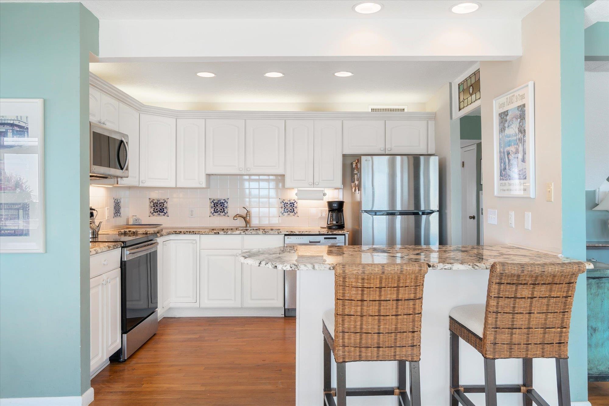 5512 Atlantic View St. Augustine, FL 32080 - Photo 13 of 77 Kitchen with white cabinetry, a kitchen bar, light stone countertops, stainless steel appliances, and decorative backsplash