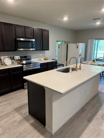 a kitchen with kitchen island granite countertop a sink a stove top oven a refrigerator and cabinets