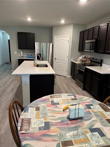 a kitchen with stainless steel appliances wooden floor dining table and chairs