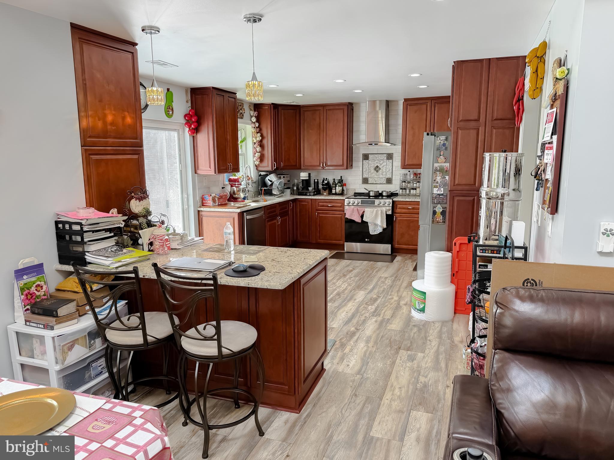 30150 Huntt Road Mechanicsville, MD 20659 - Photo 15 of 40 a kitchen with stainless steel appliances kitchen island granite countertop a dining table chairs and a refrigerator
