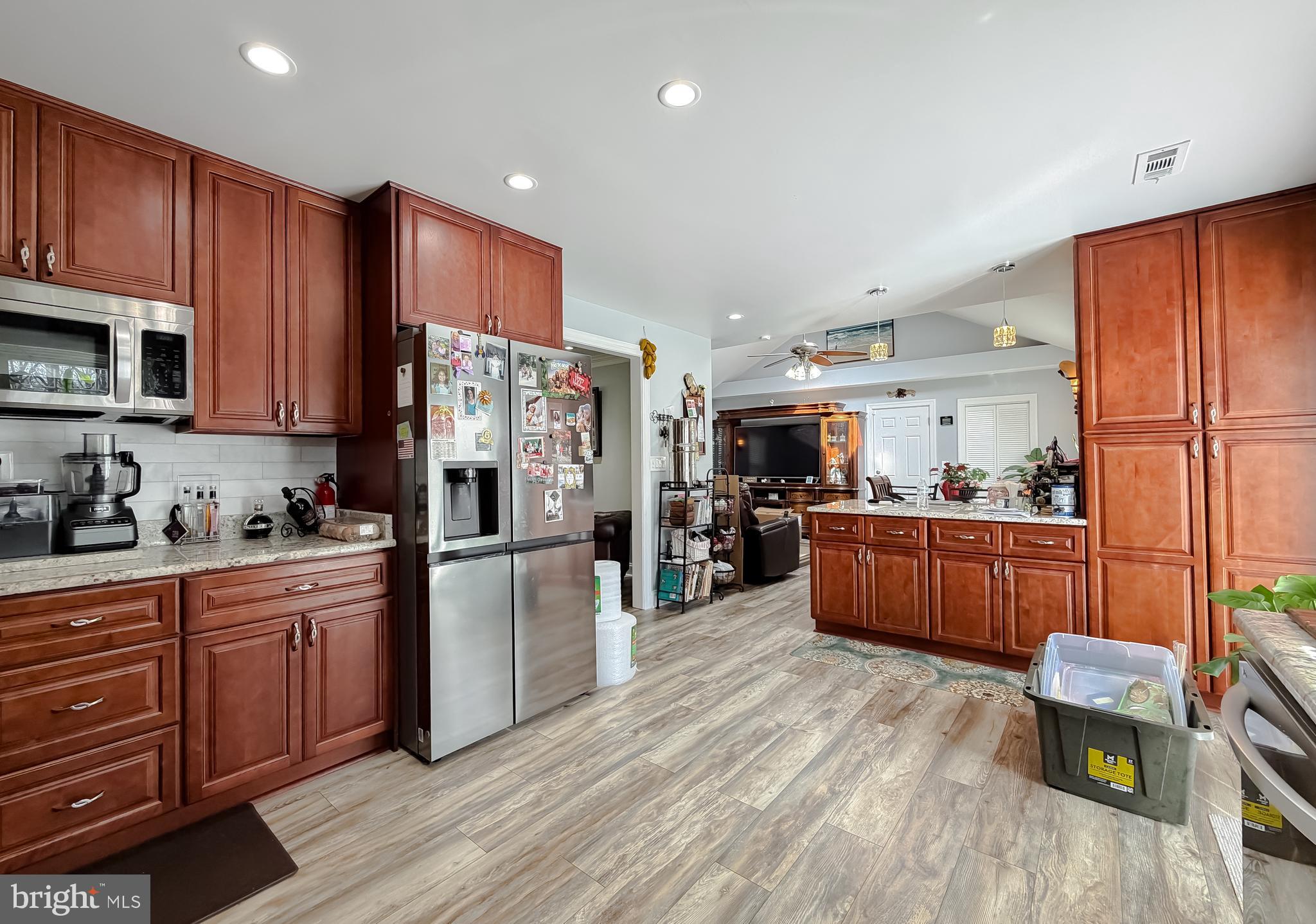 30150 Huntt Road Mechanicsville, MD 20659 - Photo 18 of 40 a kitchen with stainless steel appliances wooden floors wooden cabinets a stove a sink and a refrigerator