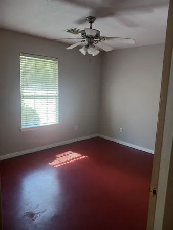 an empty room with a window and a fan