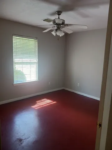 an empty room with a window and a fan