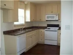 a kitchen with granite countertop white cabinets and white appliances