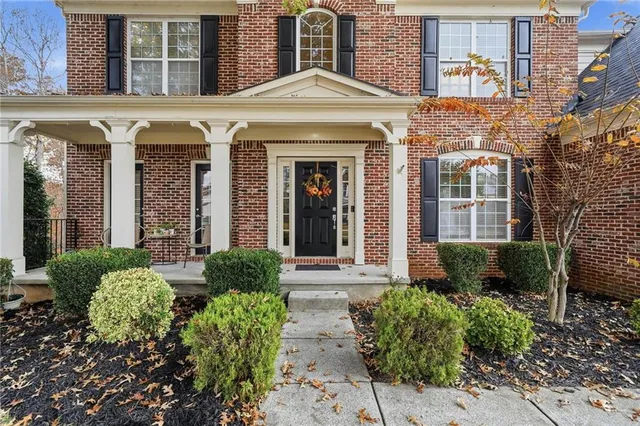 front view of a brick house with a large windows and a flower plants