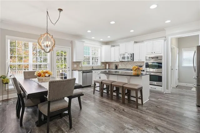 a large kitchen with stainless steel appliances granite countertop a stove a sink and white cabinets