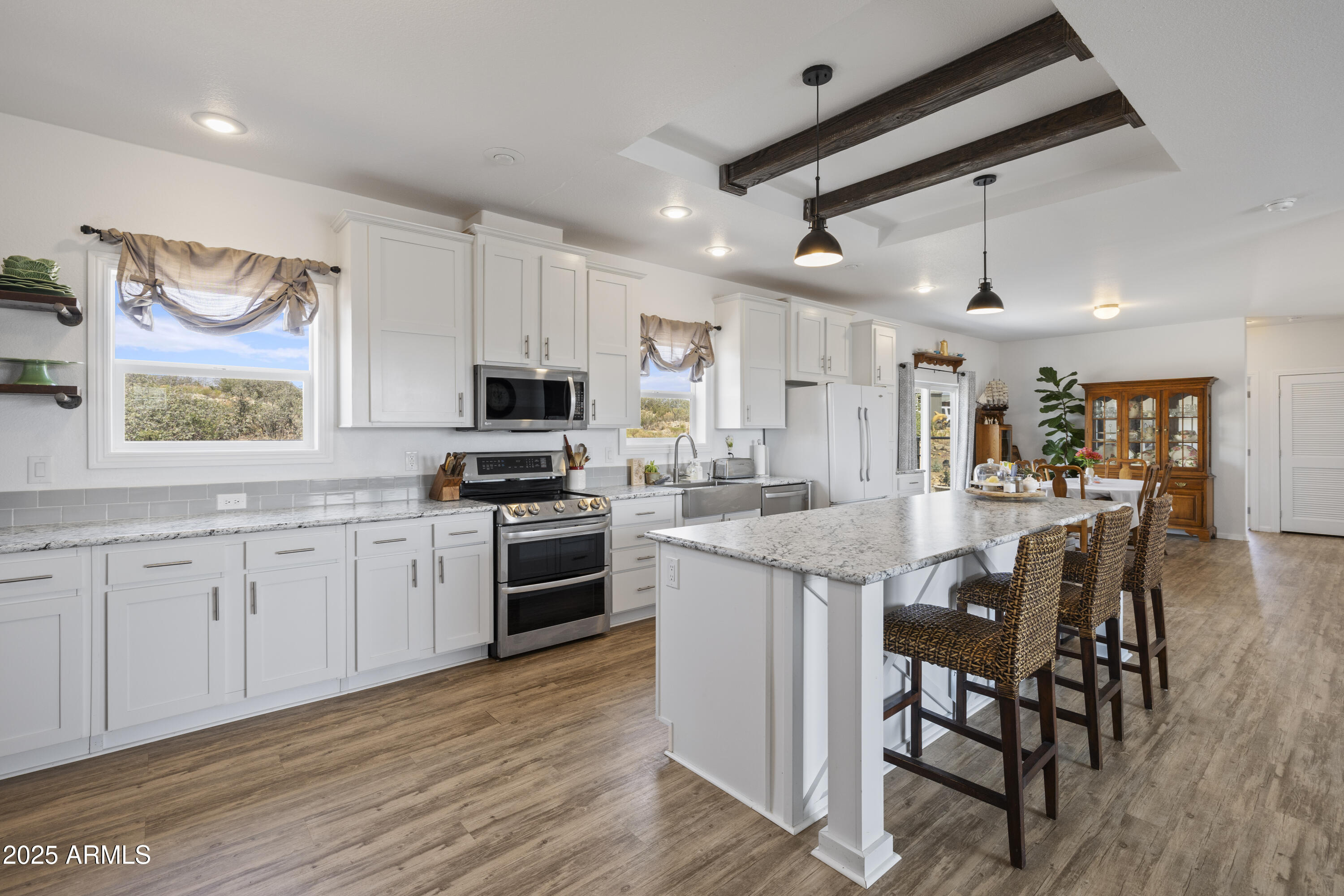1235 North Harvest Road Dewey, AZ 86327 - Photo 6 of 37 a kitchen with stainless steel appliances kitchen island granite countertop a stove top oven a sink a dining table and chairs with wooden floor