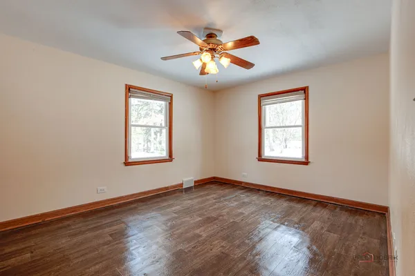 a view of an empty room with window and wooden floor