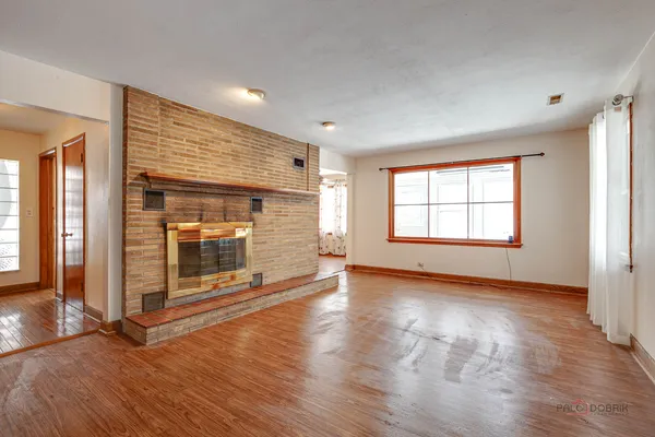 an empty room with wooden floor fireplace and windows