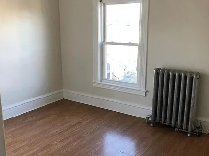 an empty room with wooden floor and a window