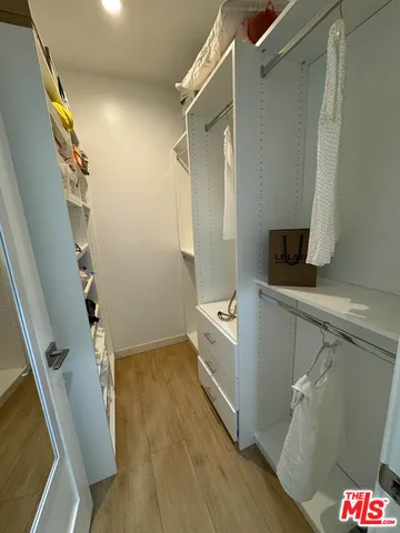 a view of walk in closet with clothes and shoes