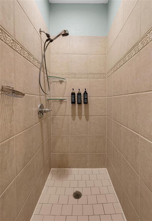 37 Bluebonnet Loop Morgan's Point Resort, TX 76513 - Photo 21 of 38 Tiled shower stall featuring a handheld showerhead, decorative accent tile band, and integrated glass shelving