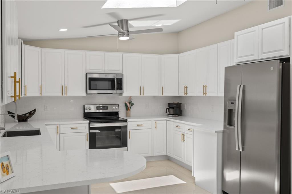 482 Trade Winds Avenue Naples, FL 34108 - Photo 13 of 26 a kitchen with white cabinets and stainless steel appliances